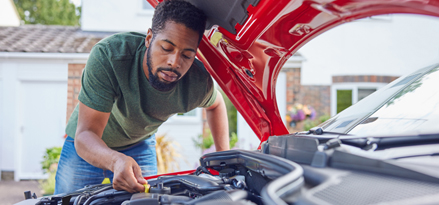 A person fixing his car with the car bonnet up